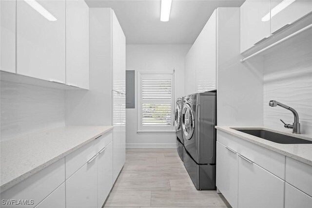 washroom with washer and dryer, cabinets, light wood-type flooring, and sink