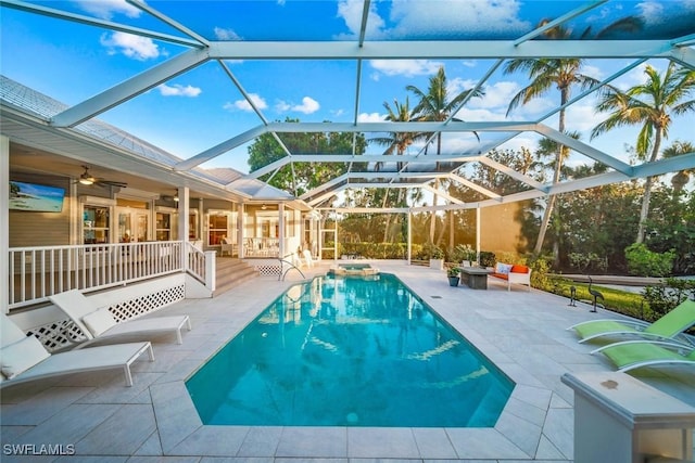 view of swimming pool featuring glass enclosure, ceiling fan, and a patio