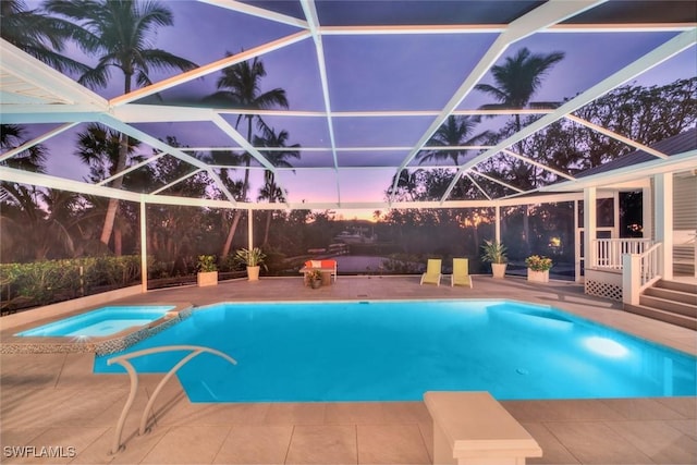 pool at dusk with glass enclosure, an in ground hot tub, and a patio