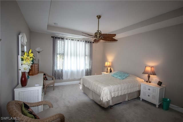 bedroom with ceiling fan, carpet flooring, and a tray ceiling