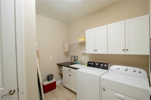 clothes washing area featuring sink, washing machine and dryer, and cabinets