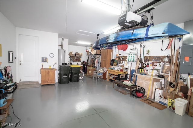 garage featuring electric panel, a garage door opener, water heater, and a workshop area