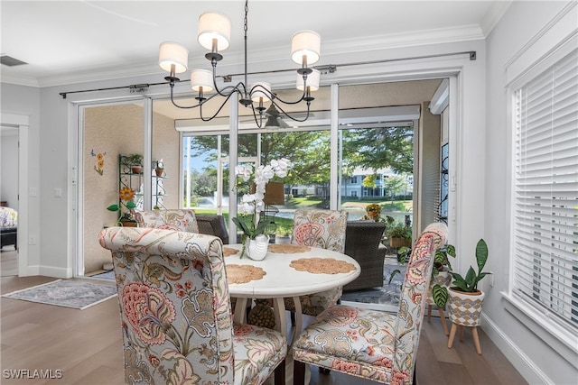 dining space with ornamental molding, a chandelier, and wood-type flooring