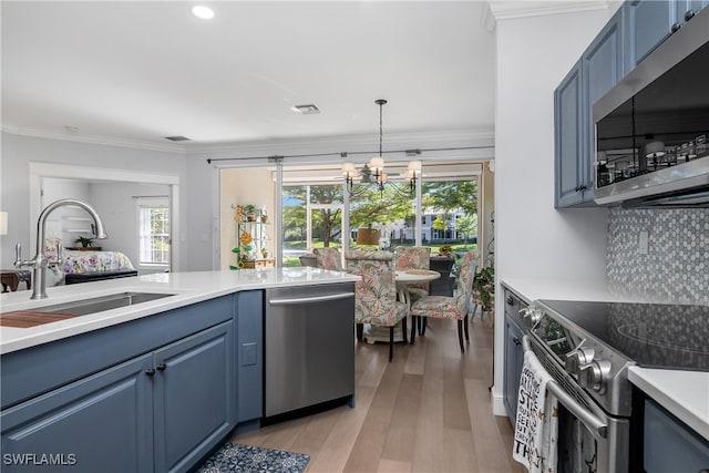 kitchen with blue cabinetry, sink, a chandelier, appliances with stainless steel finishes, and light wood-type flooring