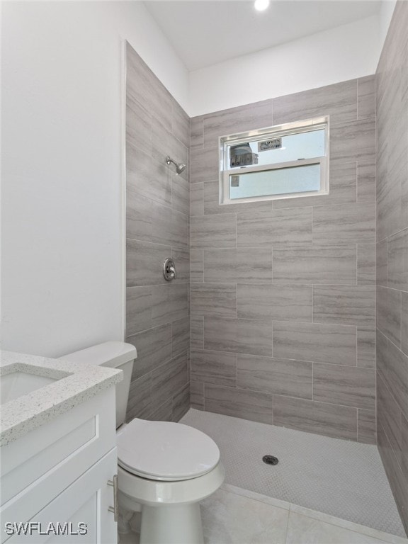 bathroom with vanity, tiled shower, toilet, and tile patterned flooring