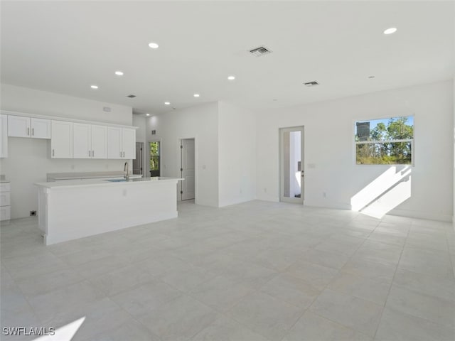 kitchen with sink, an island with sink, and white cabinetry