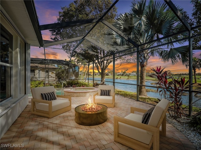 patio terrace at dusk featuring a water view and glass enclosure