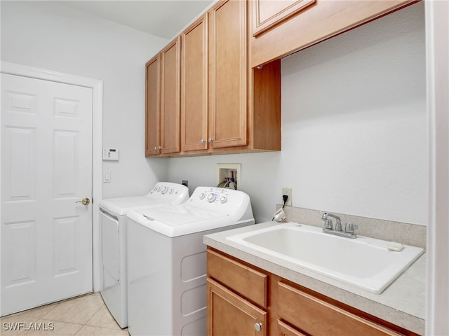 washroom with cabinets, sink, washing machine and clothes dryer, and light tile patterned floors