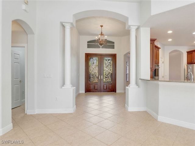 foyer entrance featuring french doors, light tile patterned flooring, and an inviting chandelier