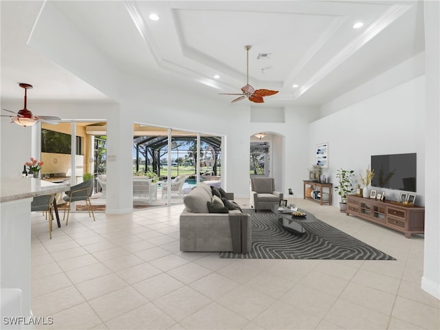 living room with light tile patterned flooring, a tray ceiling, and ceiling fan