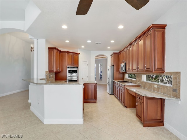 kitchen featuring kitchen peninsula, light tile patterned floors, appliances with stainless steel finishes, backsplash, and light stone countertops