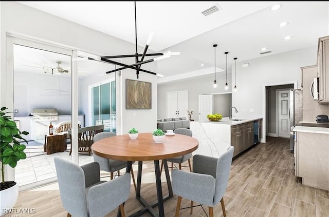 dining room with sink, a notable chandelier, and light hardwood / wood-style flooring