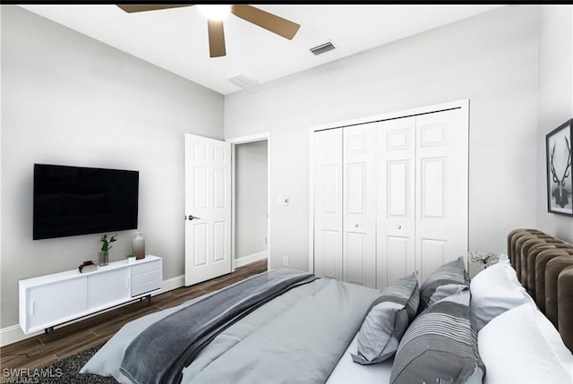 bedroom with dark wood-type flooring, ceiling fan, and a closet