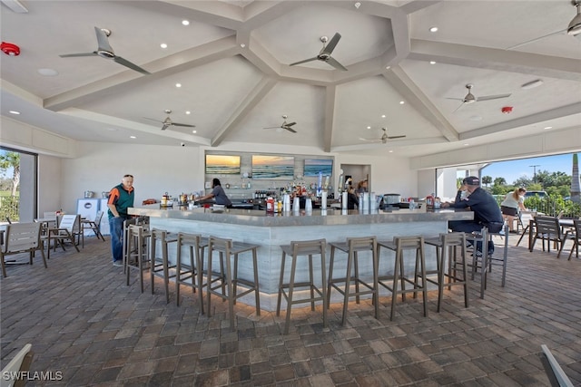 bar featuring beam ceiling, a healthy amount of sunlight, and high vaulted ceiling