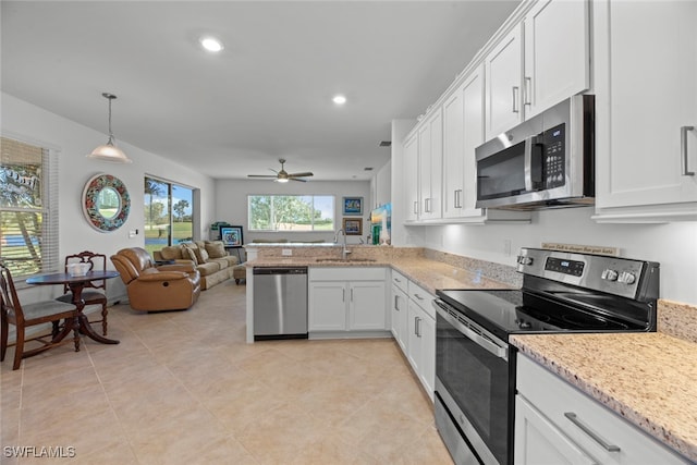 kitchen featuring kitchen peninsula, white cabinets, sink, decorative light fixtures, and stainless steel appliances