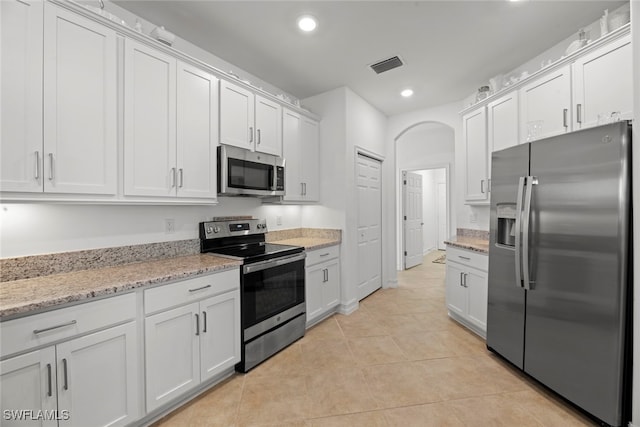 kitchen featuring light stone countertops, appliances with stainless steel finishes, white cabinets, and light tile patterned floors