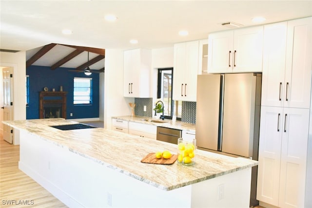 kitchen featuring white cabinets, light stone counters, beamed ceiling, and stainless steel appliances