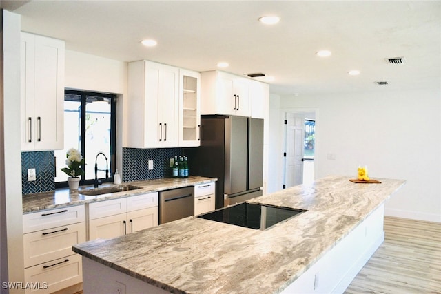 kitchen with light stone counters, white cabinetry, sink, and stainless steel appliances