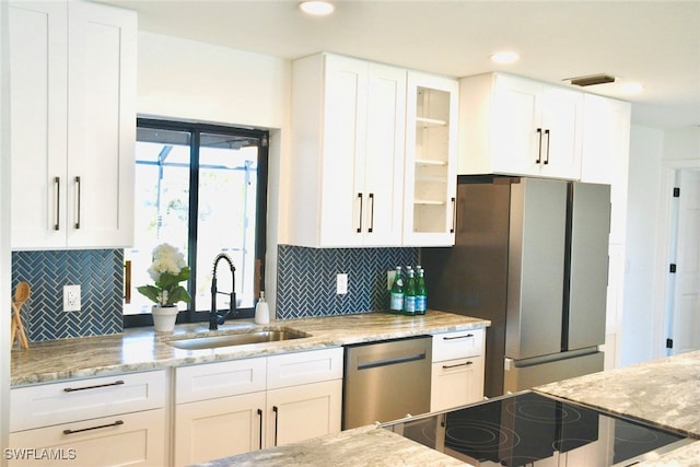 kitchen with white cabinets, stainless steel appliances, light stone counters, and sink