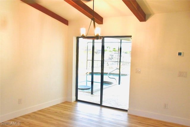 empty room with vaulted ceiling with beams, hardwood / wood-style floors, and a chandelier