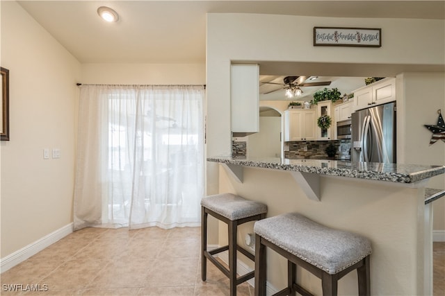 kitchen with stainless steel appliances, a breakfast bar area, white cabinetry, and kitchen peninsula