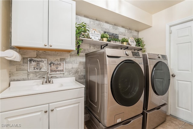 clothes washing area with light tile patterned floors, cabinets, sink, and washing machine and clothes dryer