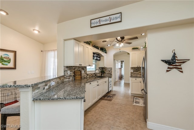 kitchen with white cabinets, a breakfast bar area, sink, and kitchen peninsula