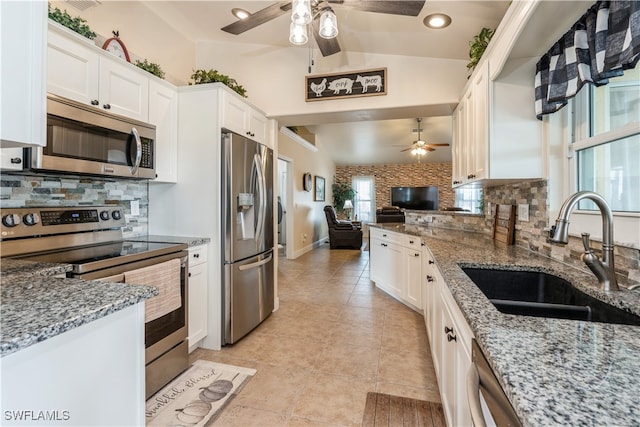 kitchen featuring a healthy amount of sunlight, appliances with stainless steel finishes, sink, and vaulted ceiling