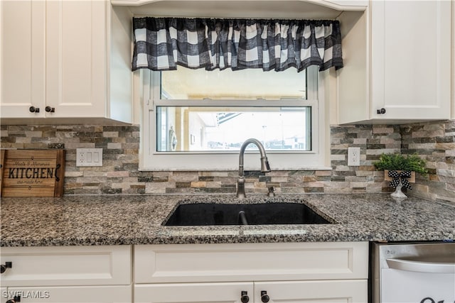 kitchen with dark stone counters, white cabinetry, backsplash, sink, and dishwasher