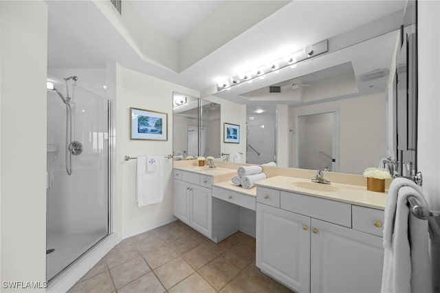 bathroom with tile patterned flooring, vanity, a tray ceiling, and walk in shower