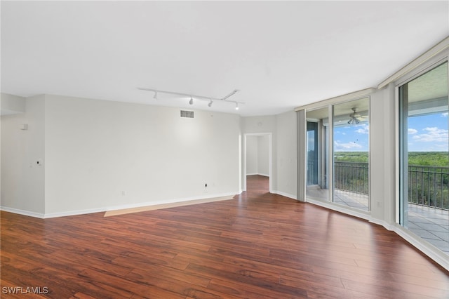 empty room featuring rail lighting and dark wood-type flooring