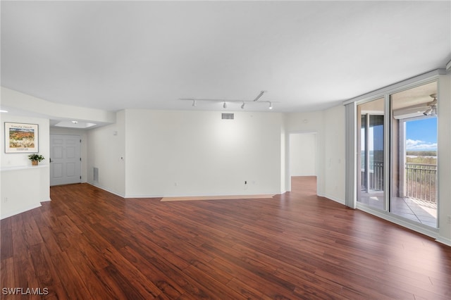 spare room with rail lighting and dark hardwood / wood-style floors