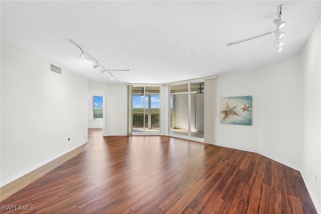 empty room with rail lighting, ceiling fan, and dark wood-type flooring