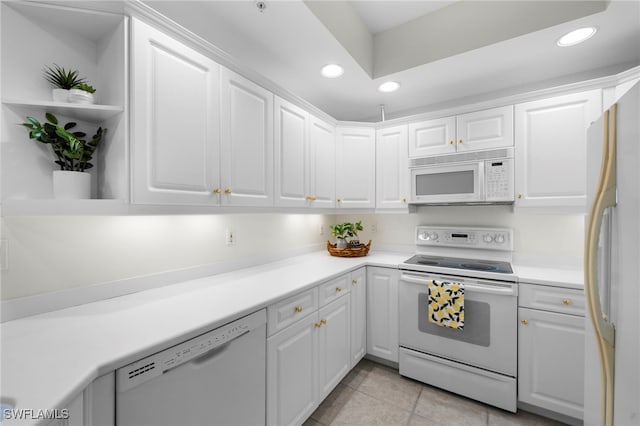 kitchen with light tile patterned floors, white cabinets, and white appliances