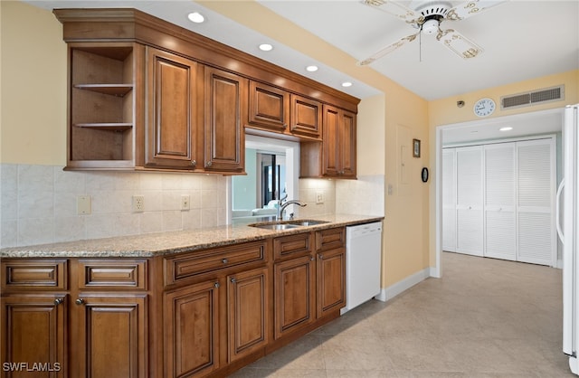 kitchen with white dishwasher, ceiling fan, light stone countertops, and sink