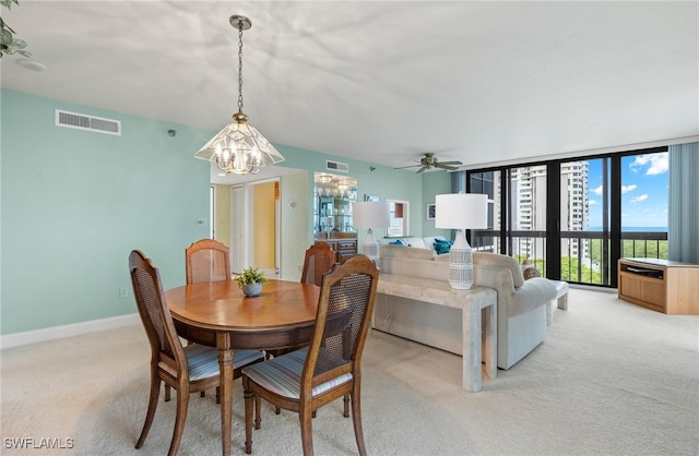 dining area with ceiling fan with notable chandelier, light colored carpet, and floor to ceiling windows