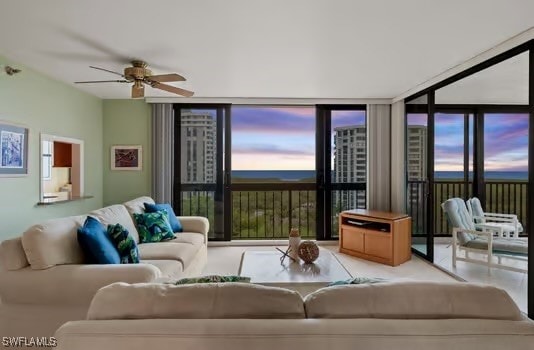 living room featuring ceiling fan and a wall of windows