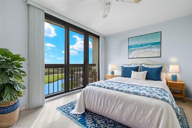 bedroom with floor to ceiling windows, a water view, carpet floors, and access to exterior