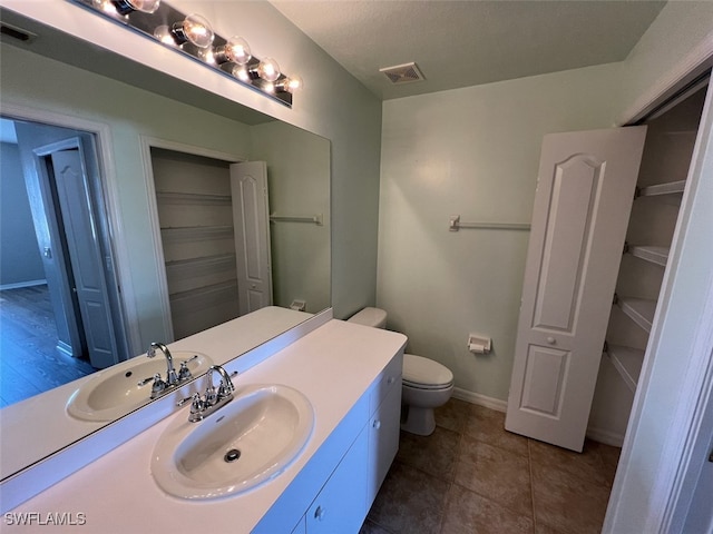 bathroom featuring toilet, vanity, and tile patterned flooring