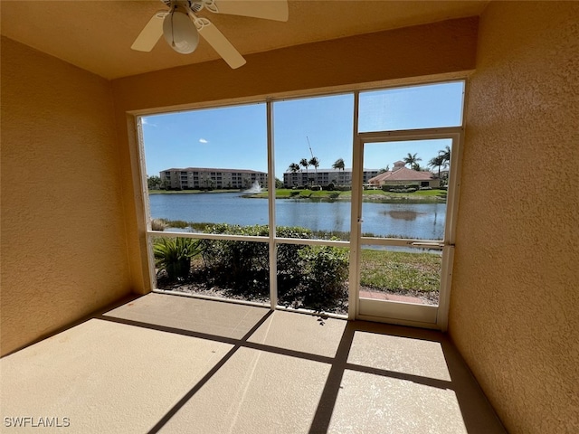 unfurnished sunroom with a wealth of natural light, a water view, and ceiling fan