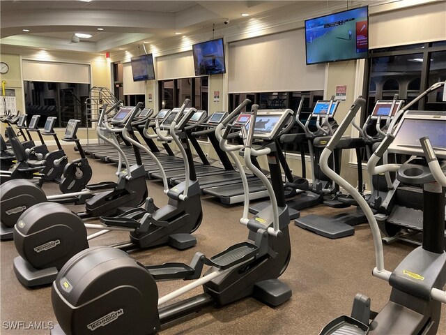 workout area with a raised ceiling and crown molding