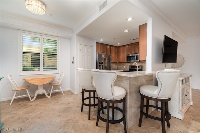 kitchen featuring stainless steel appliances, kitchen peninsula, tasteful backsplash, a kitchen breakfast bar, and crown molding