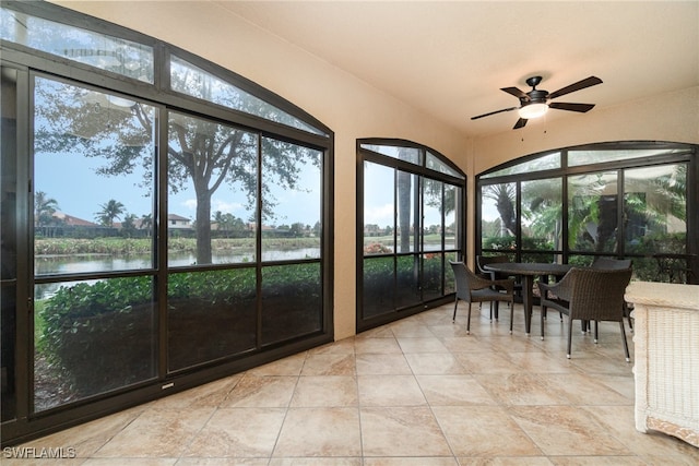 unfurnished sunroom featuring plenty of natural light, a water view, and ceiling fan