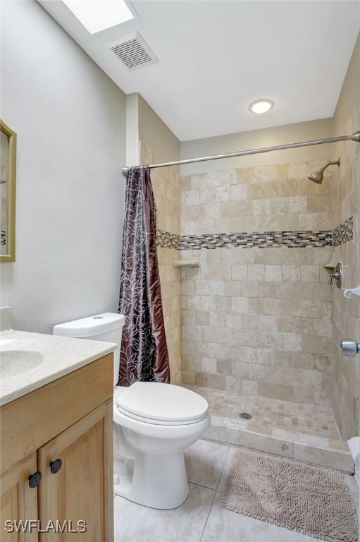 bathroom with walk in shower, toilet, a skylight, vanity, and tile patterned floors