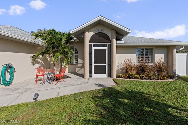 entrance to property with a patio area and a yard