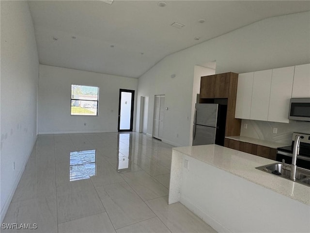 133 Greenbriar Blvd, Lehigh Acres, FL 33972 - kitchen with stainless steel microwave, freestanding refrigerator, a sink, white cabinets, and baseboards