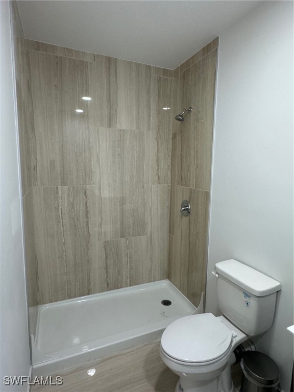 bathroom with toilet and tiled shower