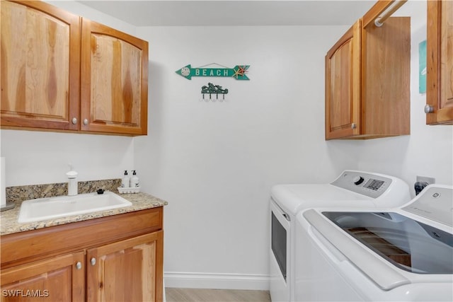 laundry area with cabinets, light hardwood / wood-style floors, washing machine and dryer, and sink