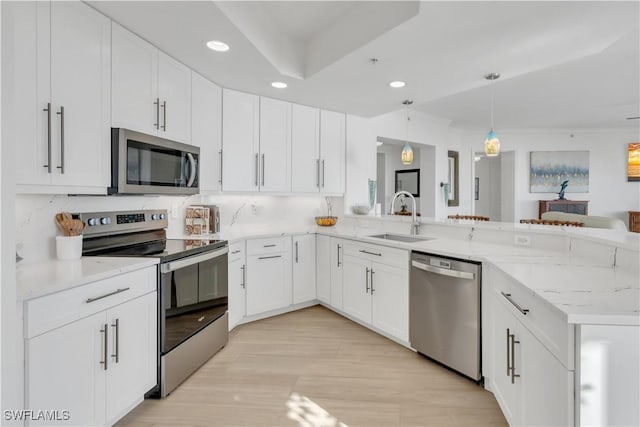 kitchen with white cabinets, sink, decorative light fixtures, kitchen peninsula, and stainless steel appliances