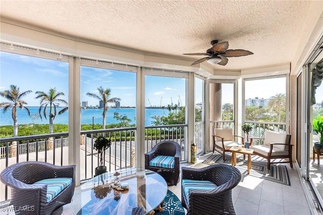 sunroom / solarium with ceiling fan and a water view